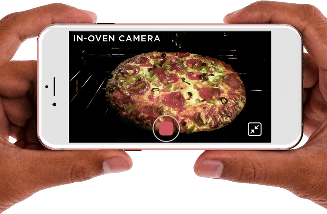 Hands holding a mobile phone viewing food cooking in oven with In-Oven Camera